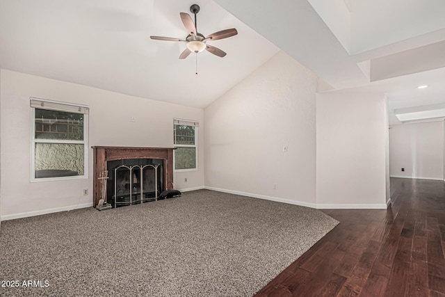 unfurnished living room featuring ceiling fan, a fireplace with raised hearth, baseboards, dark wood-type flooring, and high vaulted ceiling