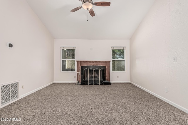 unfurnished living room with a fireplace with flush hearth, a ceiling fan, visible vents, vaulted ceiling, and carpet