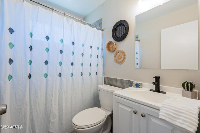 bathroom featuring toilet, vanity, and curtained shower