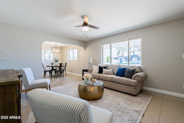 tiled living room featuring ceiling fan with notable chandelier