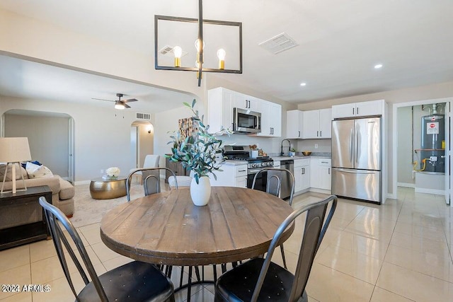 tiled dining area with sink, ceiling fan with notable chandelier, and electric water heater