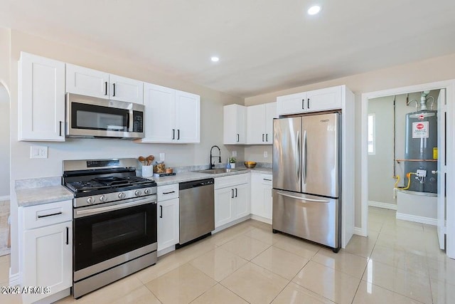 kitchen featuring stainless steel appliances, white cabinetry, sink, gas water heater, and light tile patterned flooring