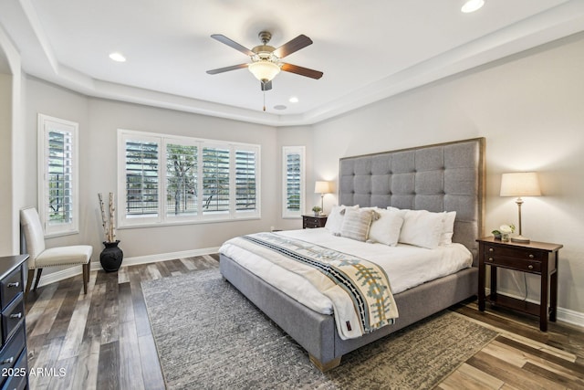 bedroom featuring hardwood / wood-style flooring, a raised ceiling, and ceiling fan