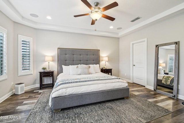 bedroom featuring dark wood-type flooring, a raised ceiling, and ceiling fan