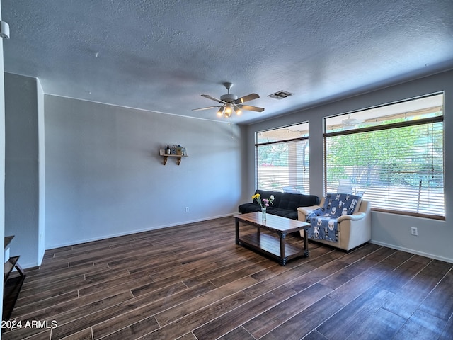 living room with ceiling fan, dark hardwood / wood-style flooring, and a textured ceiling