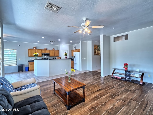 living room with ceiling fan, light wood-type flooring, and a textured ceiling