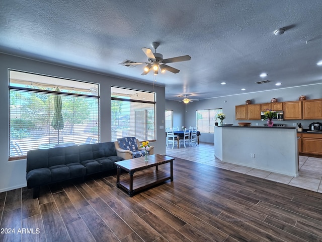 living room with hardwood / wood-style flooring, ceiling fan, and a textured ceiling