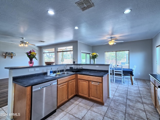 kitchen with a textured ceiling, stainless steel dishwasher, a healthy amount of sunlight, and sink