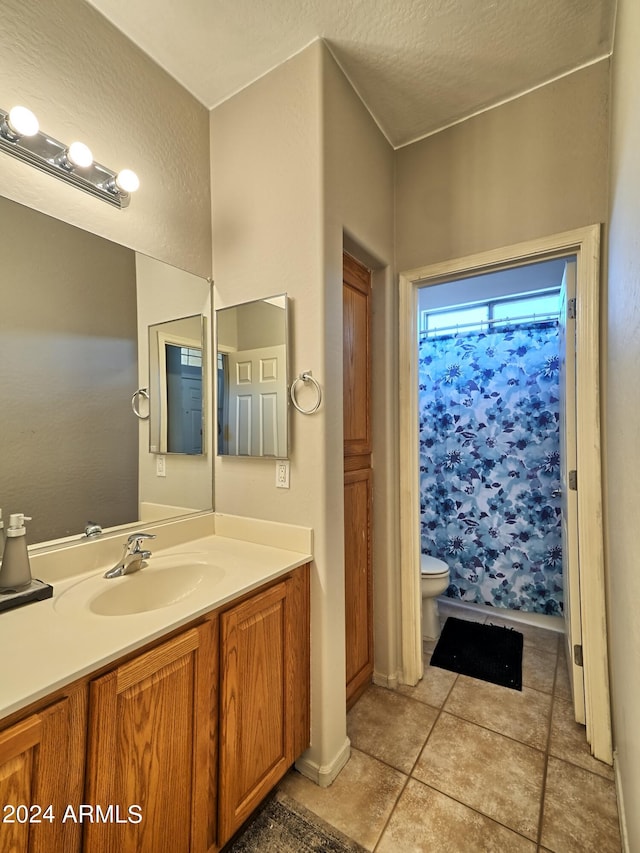 bathroom with vanity, tile patterned flooring, toilet, walk in shower, and a textured ceiling