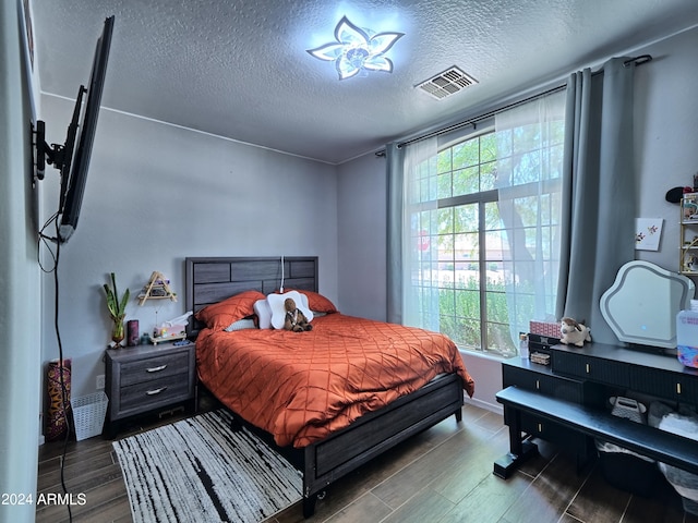 bedroom featuring a textured ceiling and dark hardwood / wood-style flooring