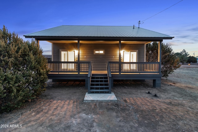 back house at dusk featuring a wooden deck