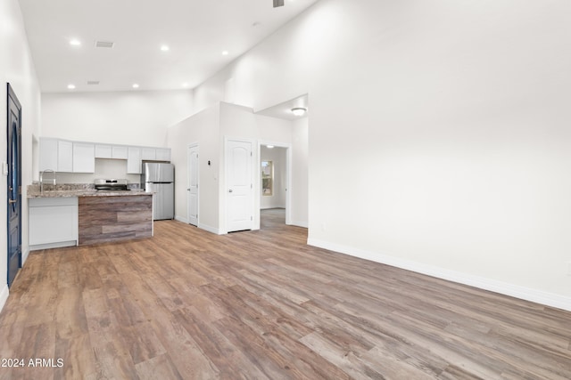 kitchen featuring light wood-type flooring, high vaulted ceiling, and appliances with stainless steel finishes