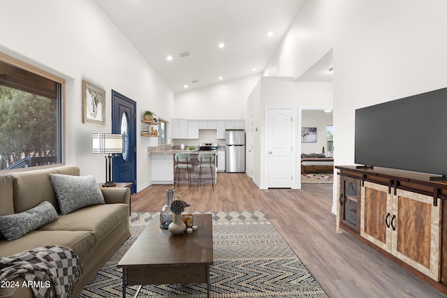 living room featuring high vaulted ceiling, light hardwood / wood-style floors, and sink