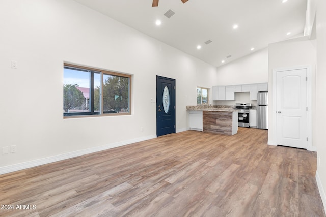 kitchen featuring white cabinetry, high vaulted ceiling, a healthy amount of sunlight, and appliances with stainless steel finishes