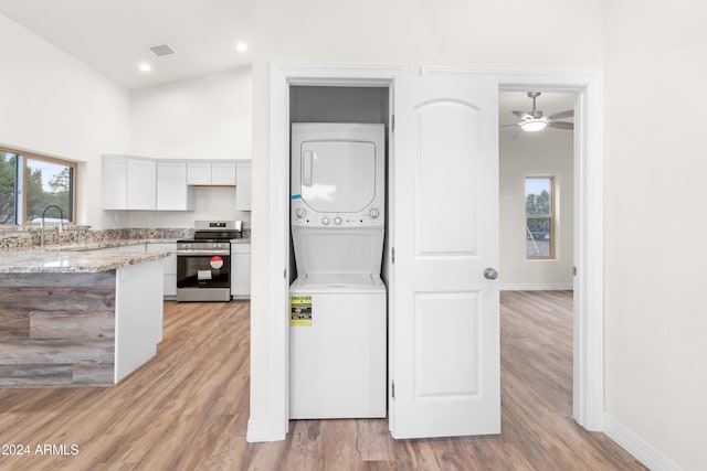 laundry room featuring stacked washer and clothes dryer, sink, a wealth of natural light, and light wood-type flooring