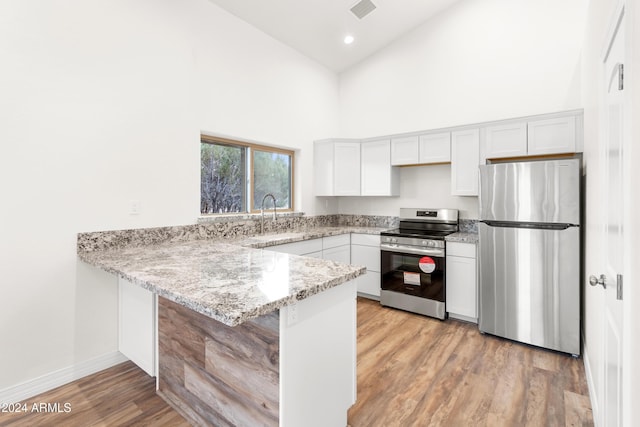 kitchen with white cabinetry, stainless steel appliances, kitchen peninsula, and sink