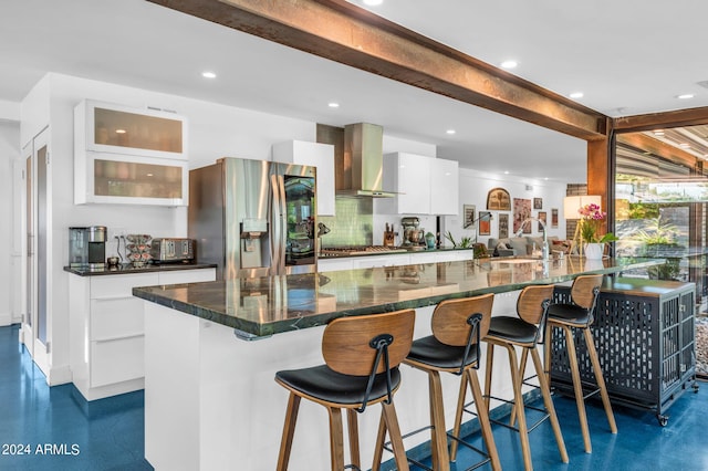 kitchen featuring wall chimney exhaust hood, white cabinetry, stainless steel appliances, and a large island