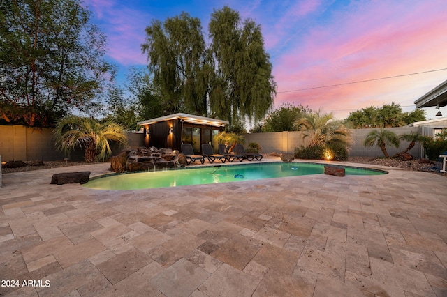 pool at dusk featuring an outbuilding and a patio