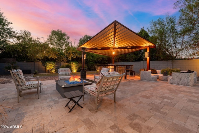 patio terrace at dusk with an outdoor living space with a fire pit