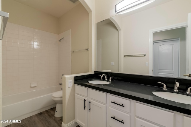 full bathroom with hardwood / wood-style flooring, toilet, vanity, and tiled shower / bath