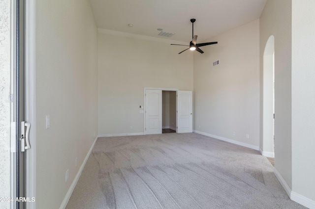 spare room with high vaulted ceiling, light carpet, and ceiling fan