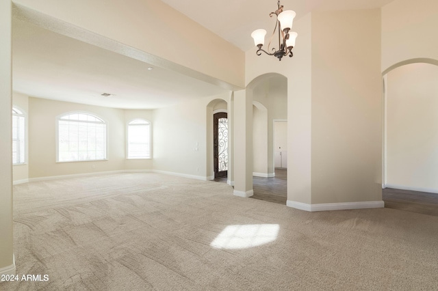 spare room featuring carpet and a chandelier