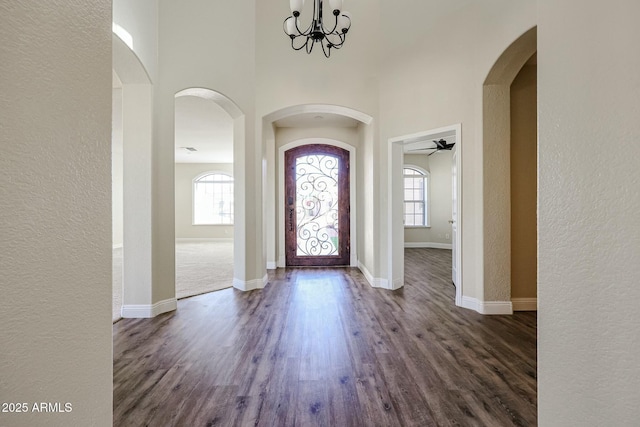 foyer entrance featuring a high ceiling, a notable chandelier, a healthy amount of sunlight, and dark hardwood / wood-style floors