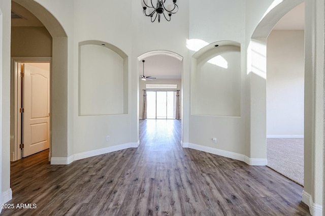 interior space with hardwood / wood-style flooring, a towering ceiling, and ceiling fan with notable chandelier