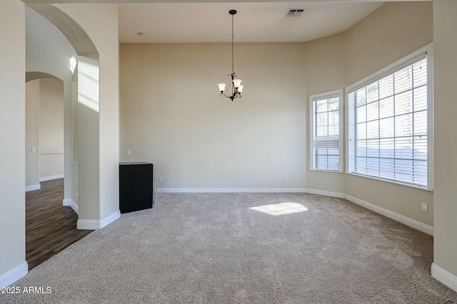 spare room with a chandelier and dark carpet