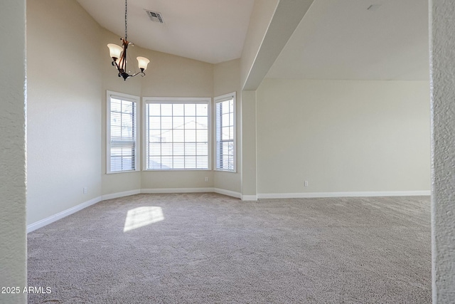 carpeted spare room featuring a notable chandelier and vaulted ceiling