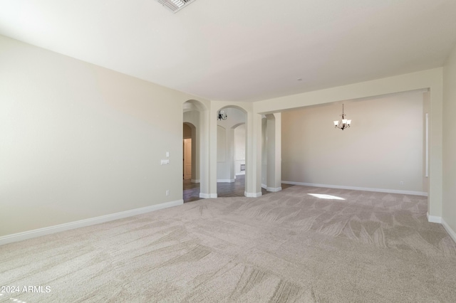 spare room featuring light colored carpet and an inviting chandelier