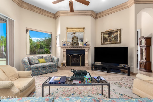 living room with a tiled fireplace, ceiling fan, and crown molding