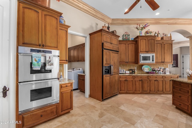 kitchen featuring separate washer and dryer, built in appliances, ceiling fan, crown molding, and light stone countertops