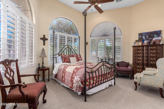 carpeted bedroom featuring multiple windows and ceiling fan