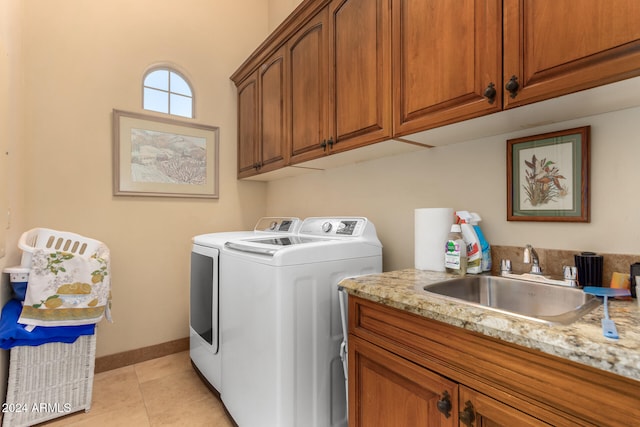 laundry area featuring washing machine and clothes dryer, light tile patterned flooring, cabinets, and sink