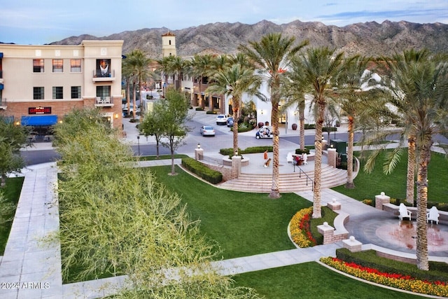 view of home's community featuring uncovered parking, a yard, and a mountain view