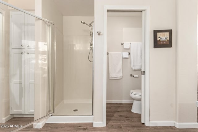 bathroom featuring toilet, wood-type flooring, and a shower with door