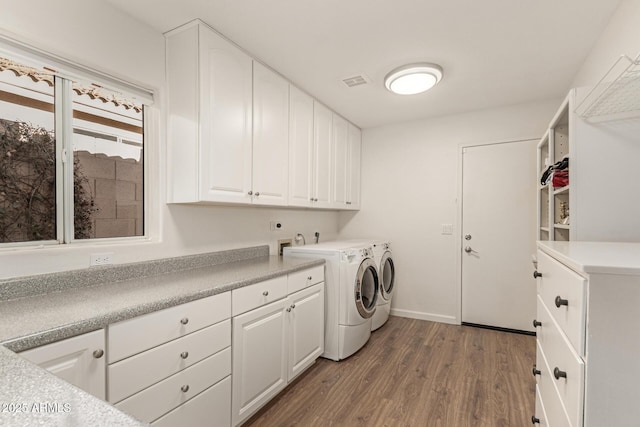 laundry room featuring separate washer and dryer, cabinets, and hardwood / wood-style floors