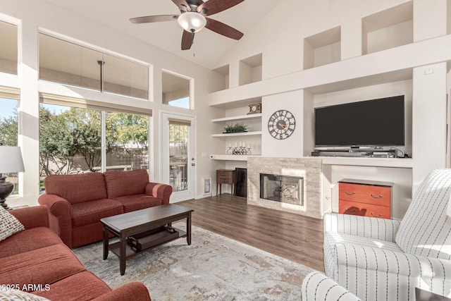 living room with high vaulted ceiling, ceiling fan, built in features, and light hardwood / wood-style flooring