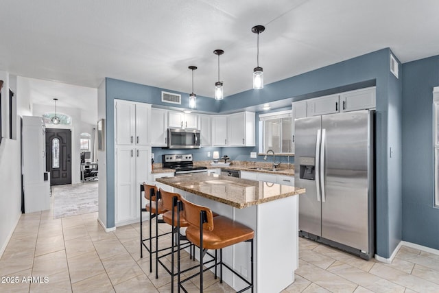 4049 E Arbor Ave, Mesa, AZ 85206 - kitchen with appliances with stainless steel finishes, a sink, white cabinets, light stone counters, and a center island