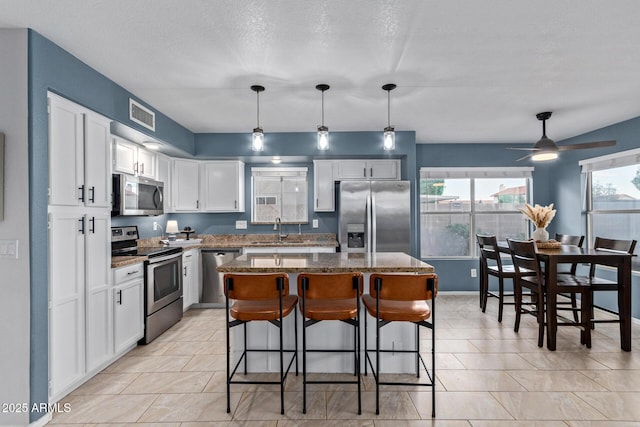 4049 E Arbor Ave, Mesa, AZ 85206 - kitchen with stainless steel appliances, a sink, white cabinetry, stone countertops, and a breakfast bar area