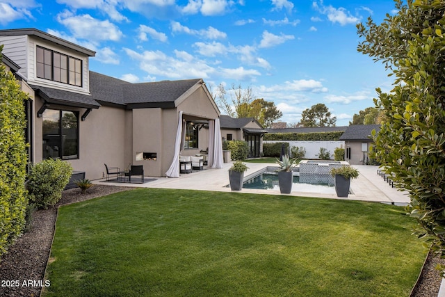 rear view of house with a swimming pool with hot tub, a lawn, and a patio