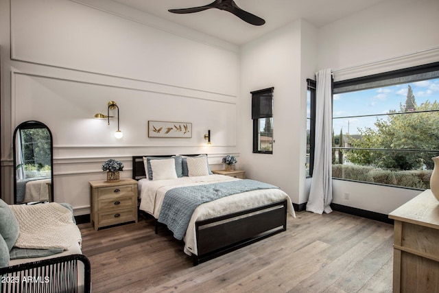 bedroom with multiple windows, hardwood / wood-style floors, and ceiling fan