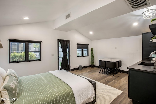 bedroom featuring vaulted ceiling, a chandelier, sink, and hardwood / wood-style flooring