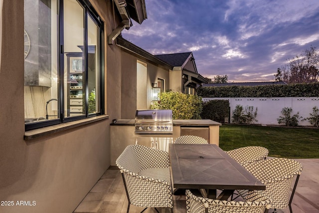 patio terrace at dusk featuring area for grilling, grilling area, and a lawn