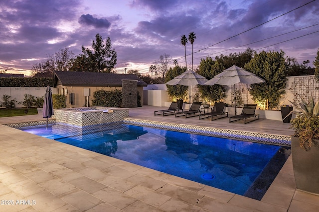 pool at dusk featuring an outdoor structure, a patio, and an in ground hot tub