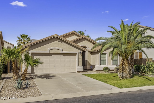 mediterranean / spanish-style home with stucco siding, driveway, a front yard, and an attached garage