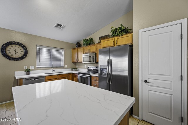 kitchen featuring light tile patterned floors, a sink, appliances with stainless steel finishes, and lofted ceiling