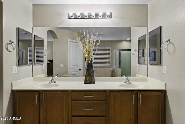 full bath with a shower stall, double vanity, and a sink