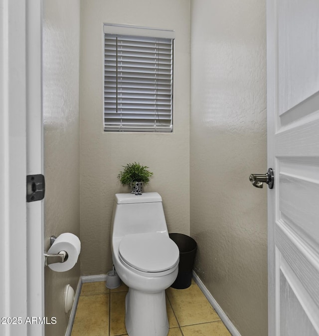 bathroom with baseboards, tile patterned floors, and toilet